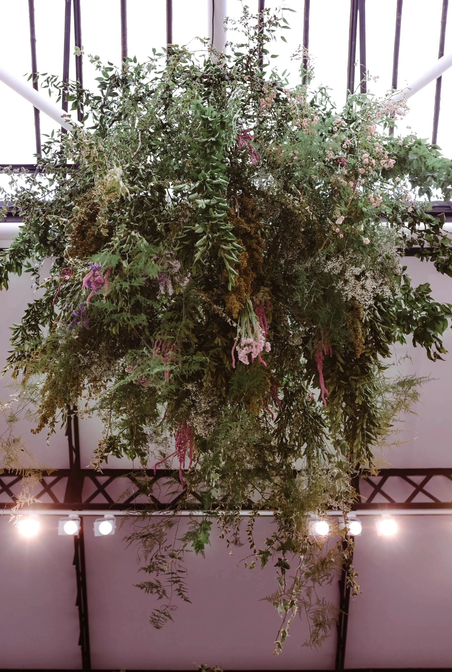 Suspension de plantes luxuriantes sous un toit en verre dans un espace intérieur lumineux.