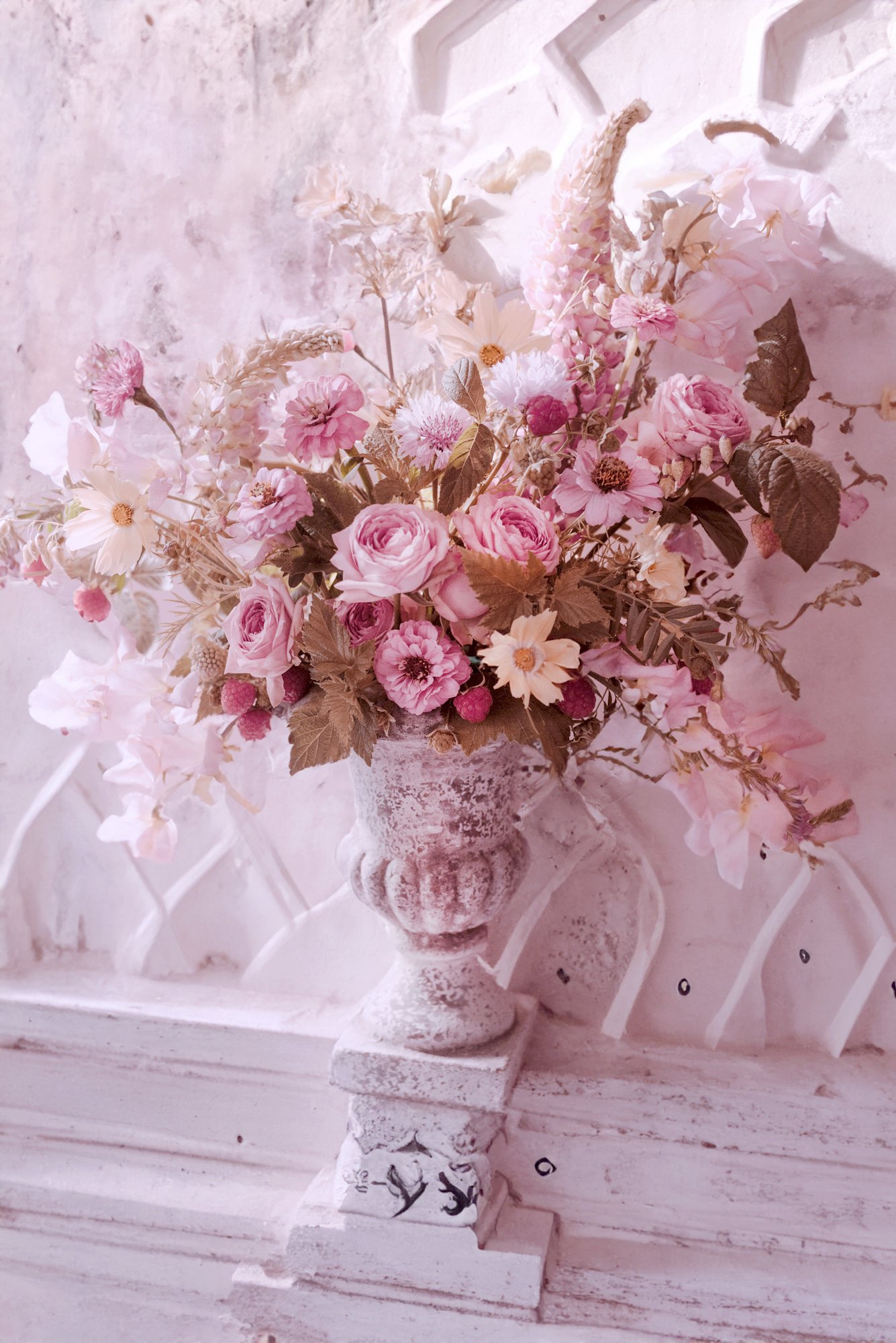 Bouquet de fleurs roses et blanches dans un vase décoratif sur un fond texturé.