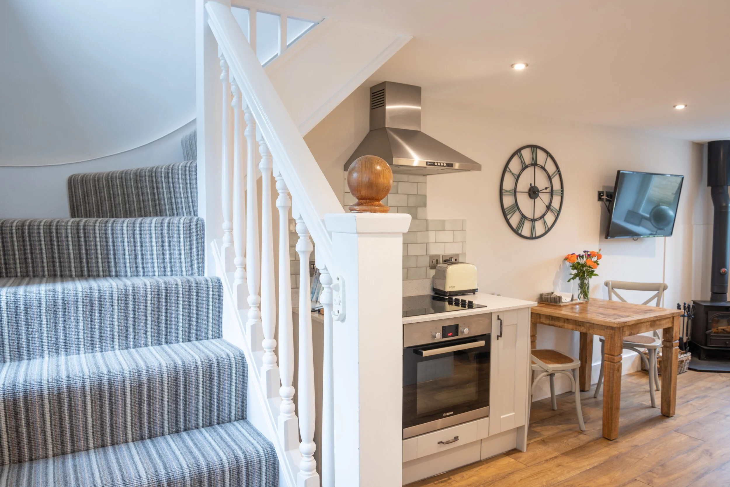 A beautifully renovated open-plan holiday let kitchen and dining space featuring a stylish staircase