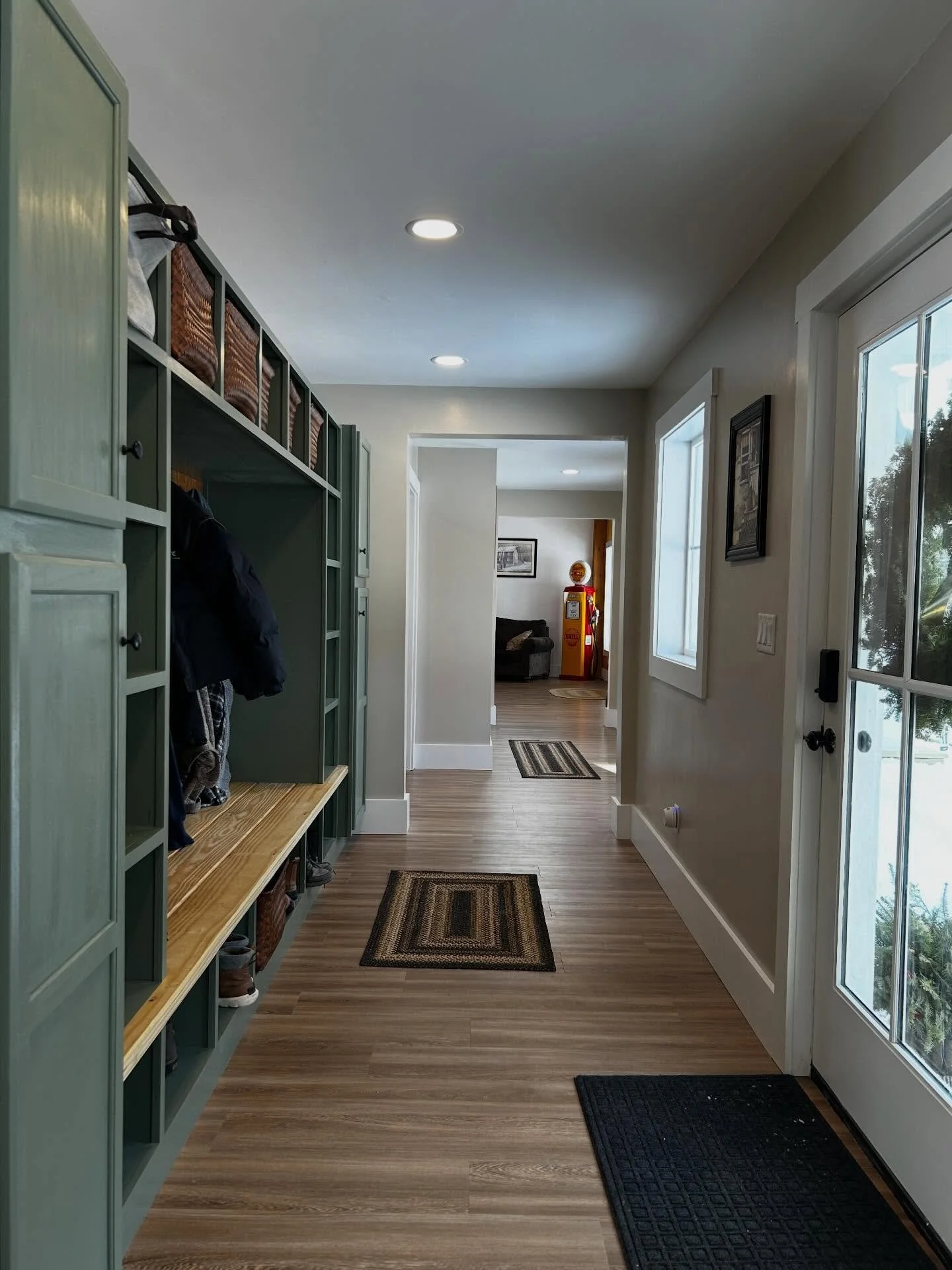 Function meets high-end craftsmanship in this mudroom transition. From the custom sage built-ins to the warm wood accents, this space was designed to handle the chaos of daily life without sacrificing a bit of style and positioned to provide easy acc