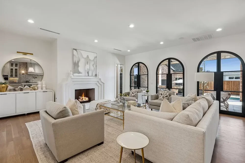Luxury staged living room with arched windows and fireplace in a West Plano home