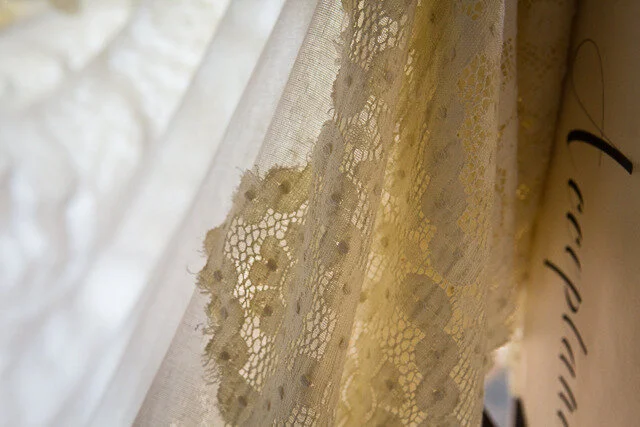 Close-up of a lace curtain with floral patterns, partially drawn.
