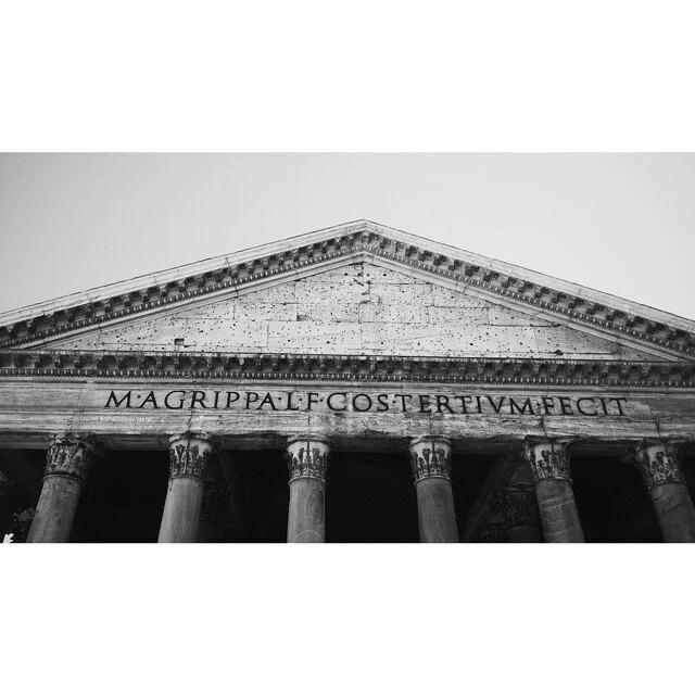 Black and white photo of the front of the Pantheon in Rome, Italy, showing columns and a Latin inscription.