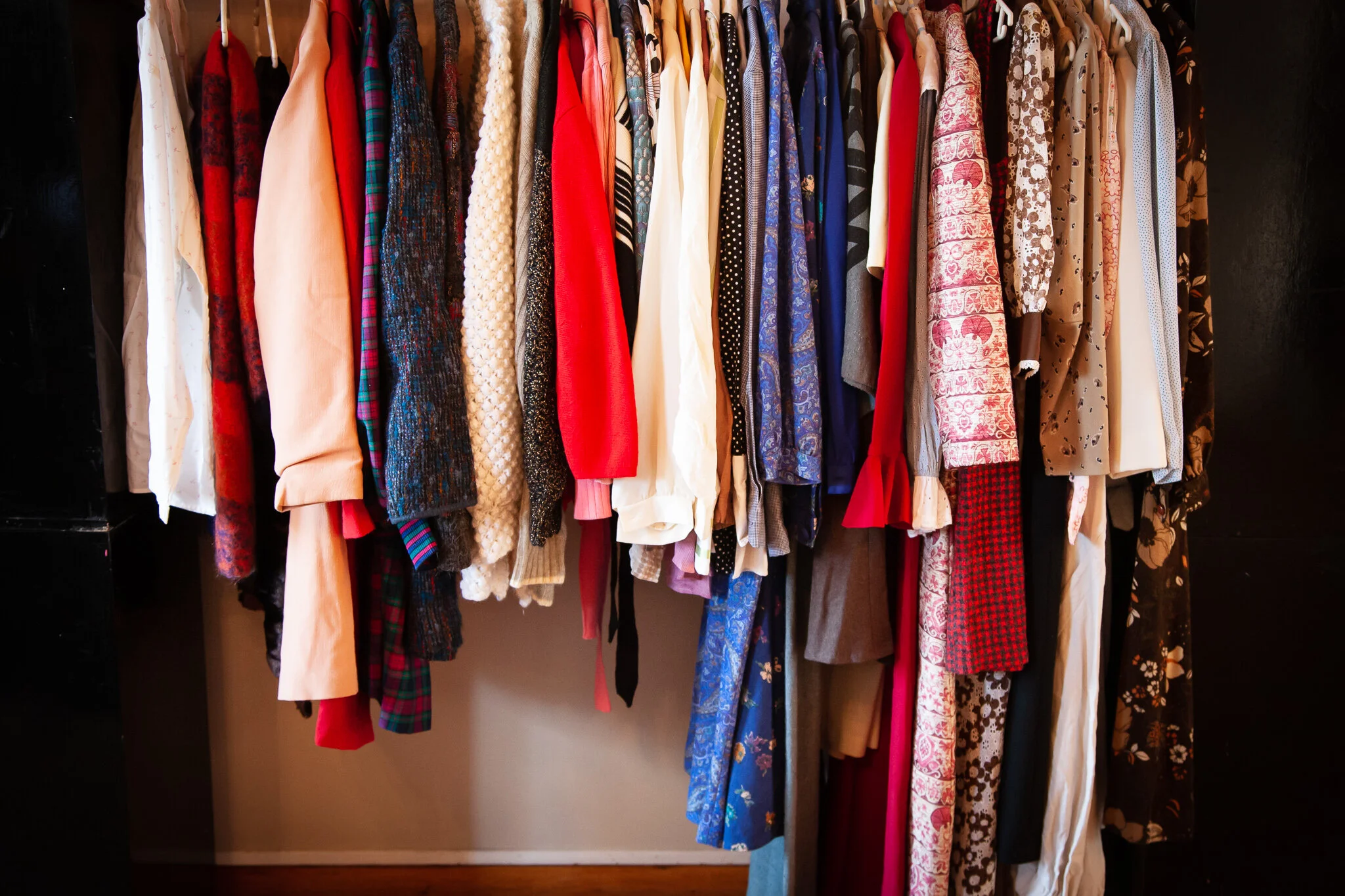 A collection of various colorful clothes hanging on a rack.