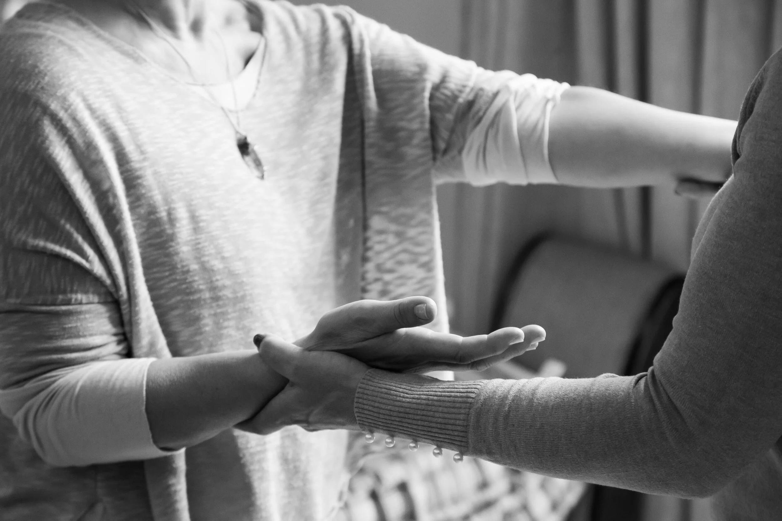 Two people holding hands, with one person touching the other's arm in a comforting manner.
