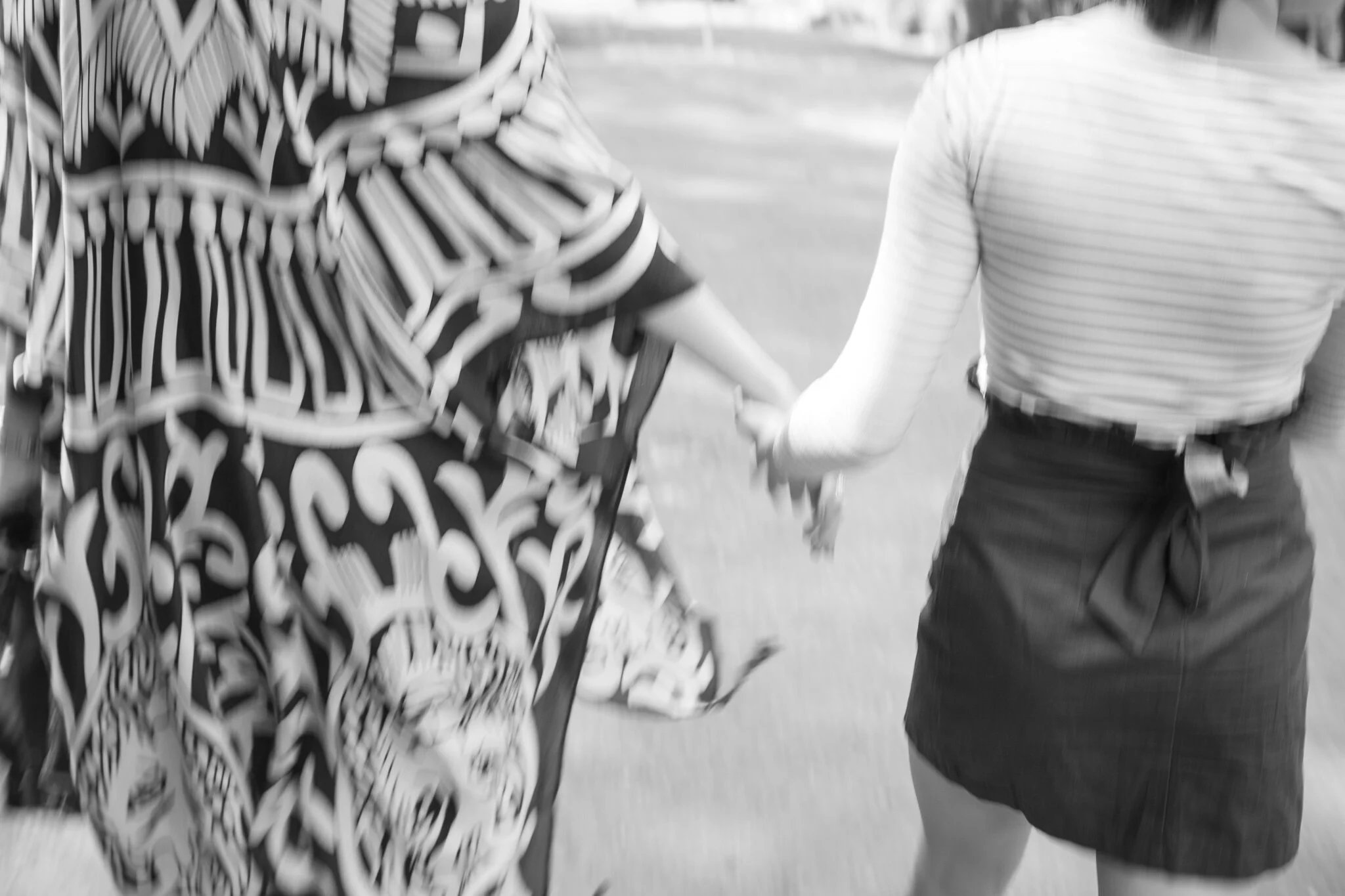 Mother and daughter holding hands, walking together outside.