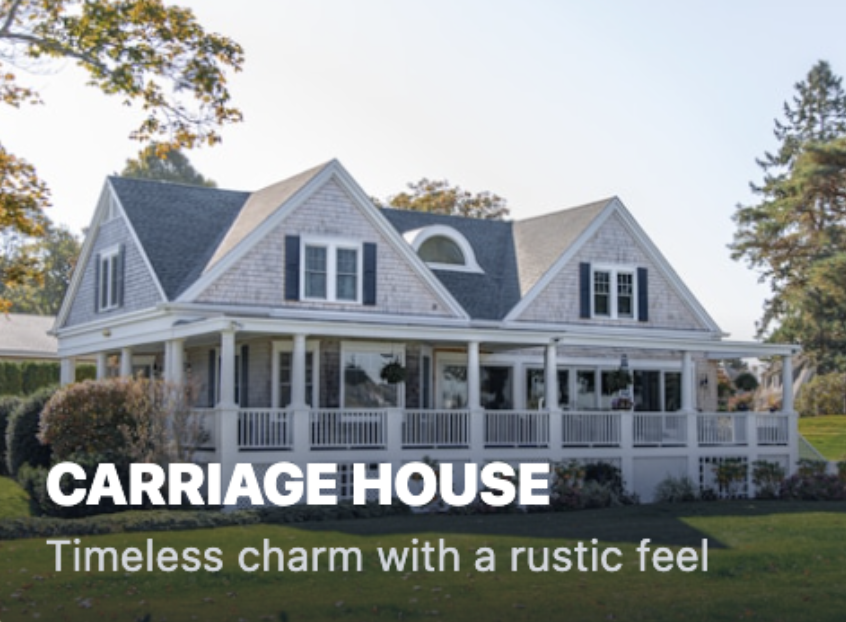 A large, two-story house with a wraparound porch, white railings, black shutters, and gabled roof, surrounded by trees and a lawn.