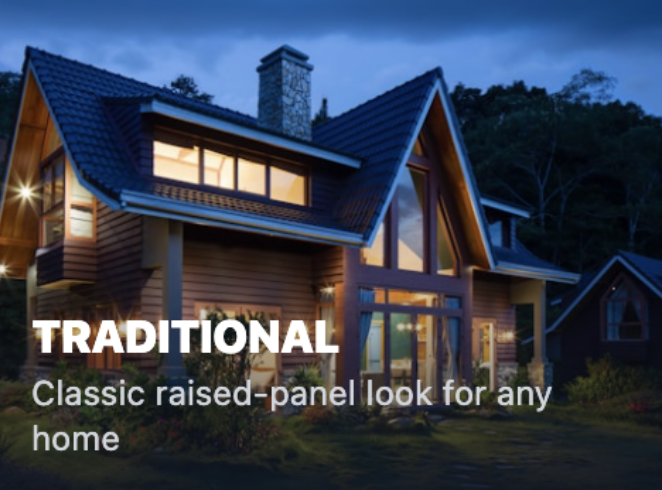 Photo of a traditional house at dusk with large glass windows and a steep roof, surrounded by trees.
