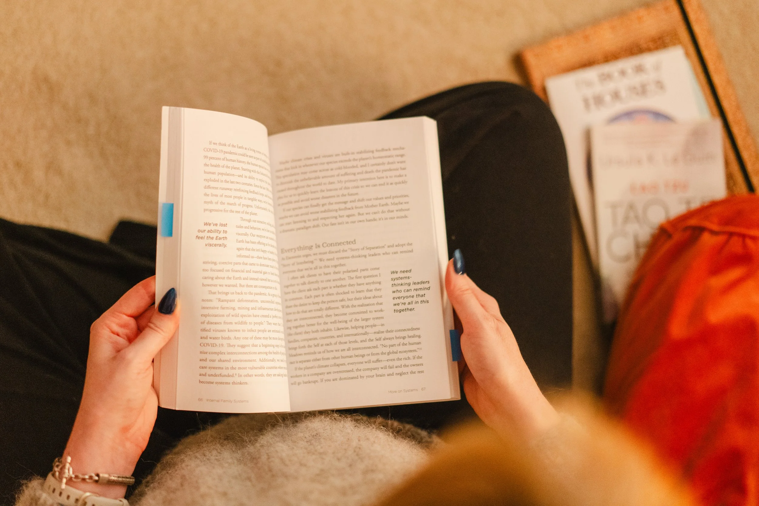 a woman reading from a book with a stack of books to her right