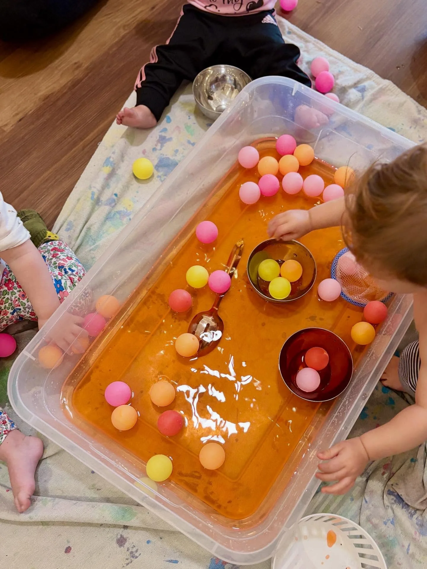 Today at Messy Minis (6-18 months), the group really enjoyed playing with the orange water, ping-pong balls, metal bowls, and spoons. We saw a lot of collecting, dumping, scooping, and sharing at this station. The sensory bags on the light table insp