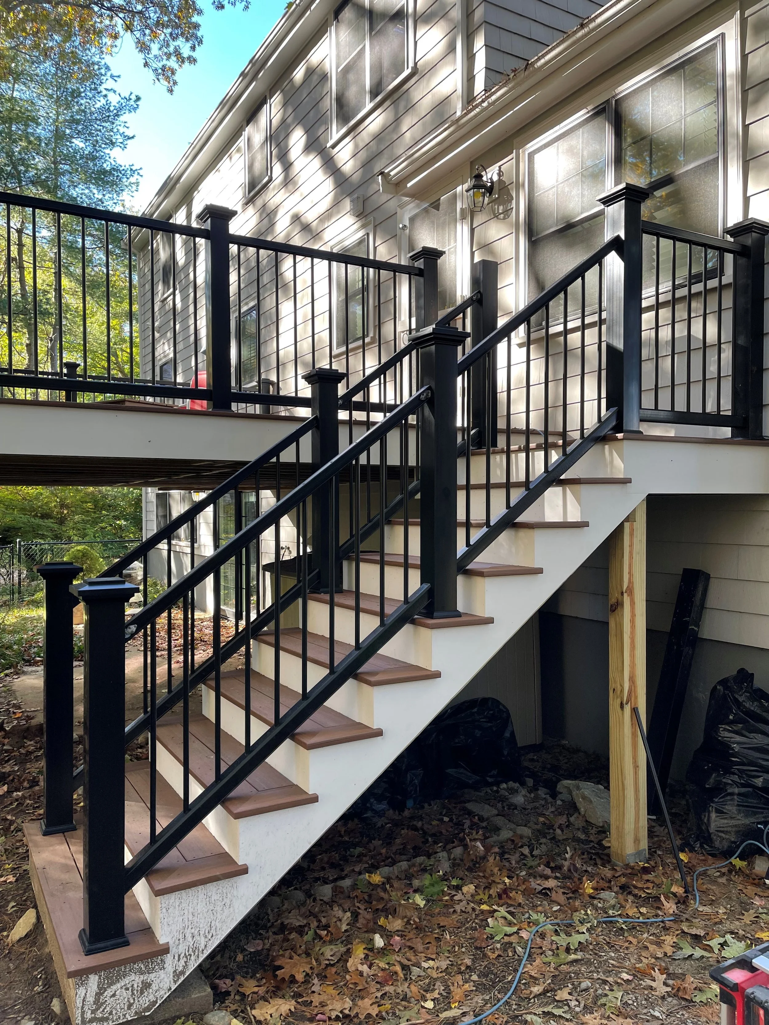 Wooden back yard deck and staircase. Harwood stained with black railings. 