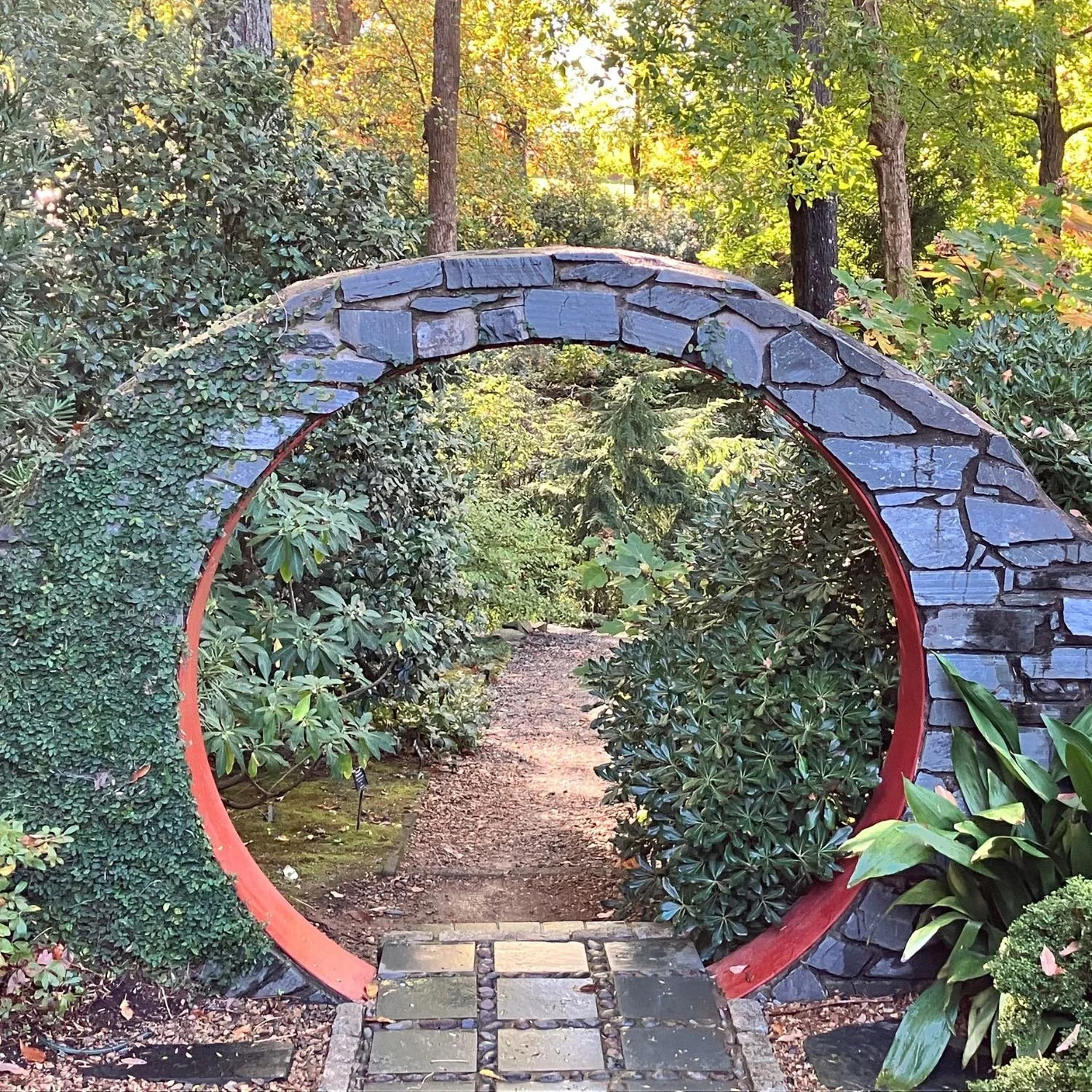 Stone garden archway framing a forest path, symbolizing new directions, alignment, and personal growth through coaching.