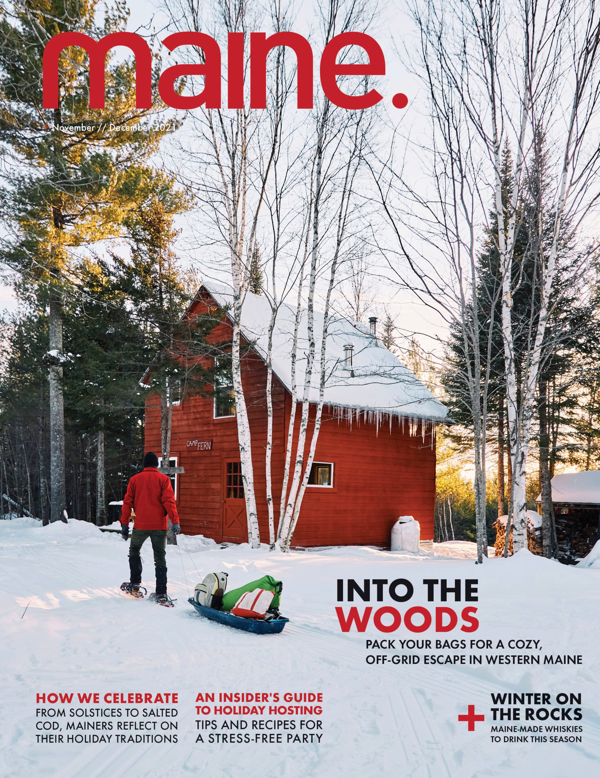 A person in a red jacket pulling a sled with gear through snow in front of a red house with icicles hanging from the roof, surrounded by bare trees and pine trees at sunset.