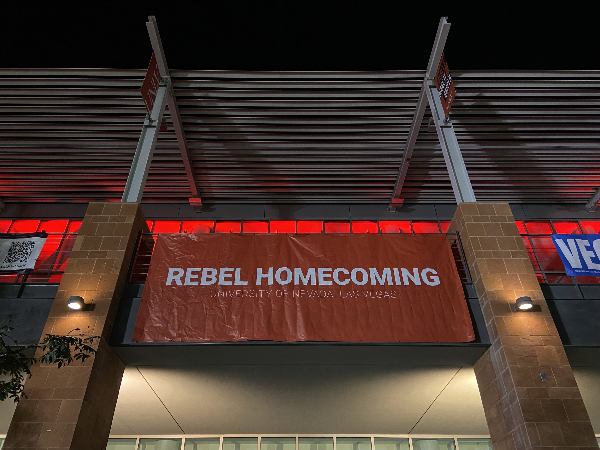 A red banner that hangs up on the Student Union building that reads, "Rebel Homecoming. University of Nevada, Las Vegas"
