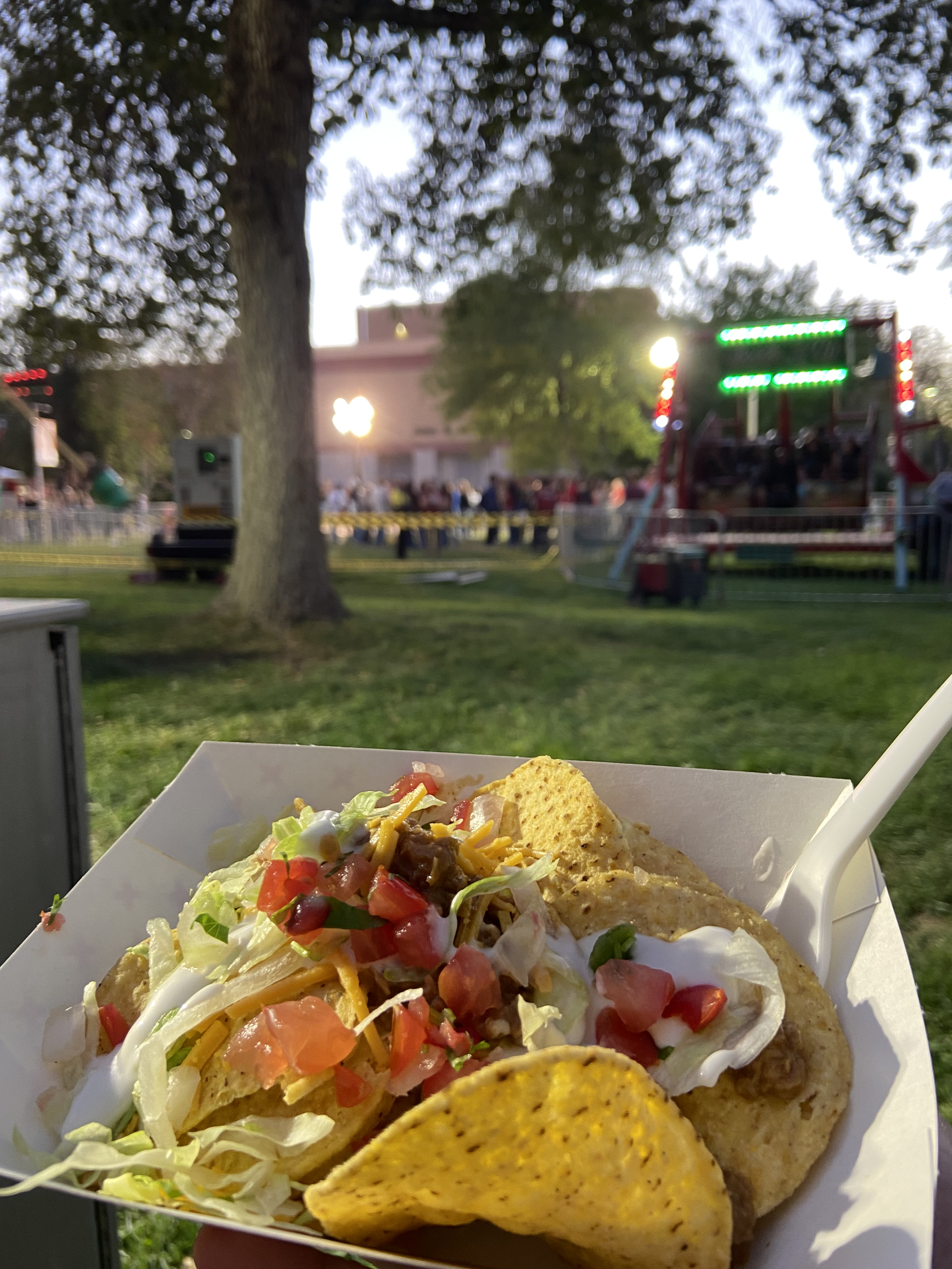 A serving of walking tacos: nachos, ground beef, shredded lettuce, salsa, and sour cream.