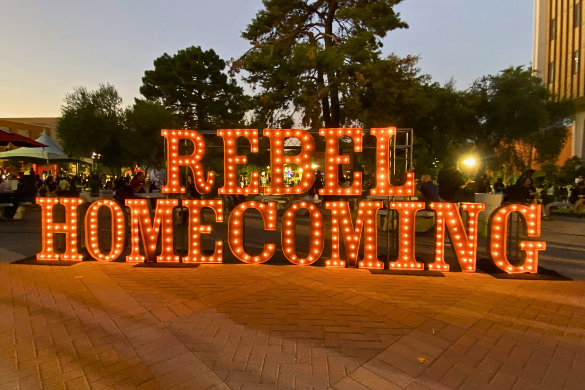 A large orange neon sign in Pida Plaza that says "Rebel Homecoming."