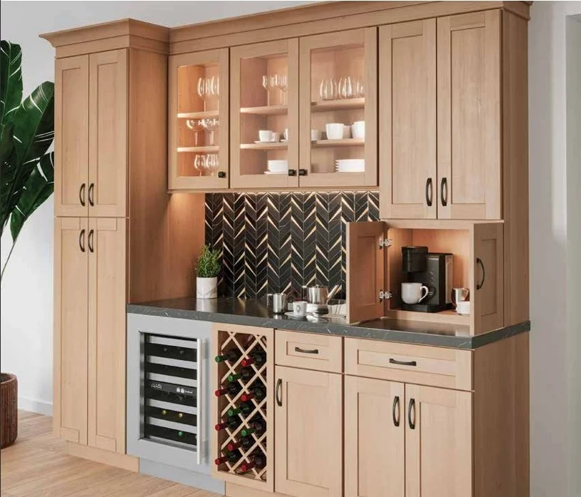 Kitchen with light wood cabinets, glass-front upper cabinets, a black chevron tile backsplash, a wine cooler, a built-in wine rack, and a coffee station with a coffee maker and cups.