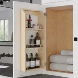 Open wall-mounted cabinet with shelves containing skincare and cosmetic products, and a stack of rolled towels on the side.