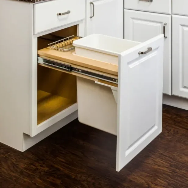Open kitchen cabinet with a pull-out trash bin, dishwasher, and countertop in a modern kitchen.