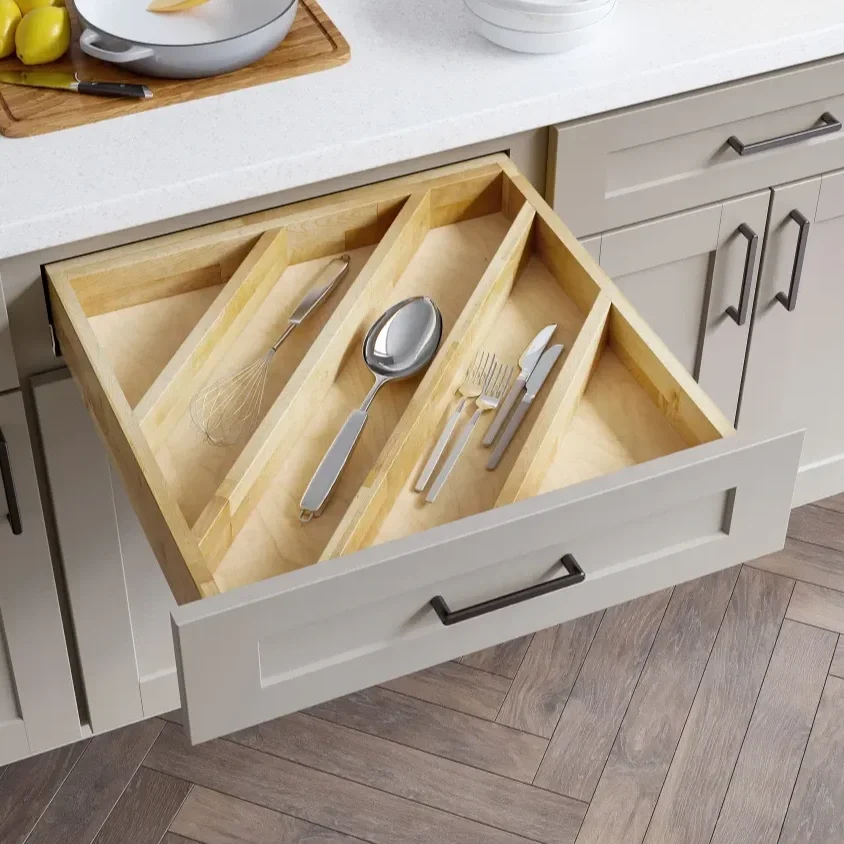 Kitchen drawer with utensil tray containing a whisk, spoon, fork, and knives.