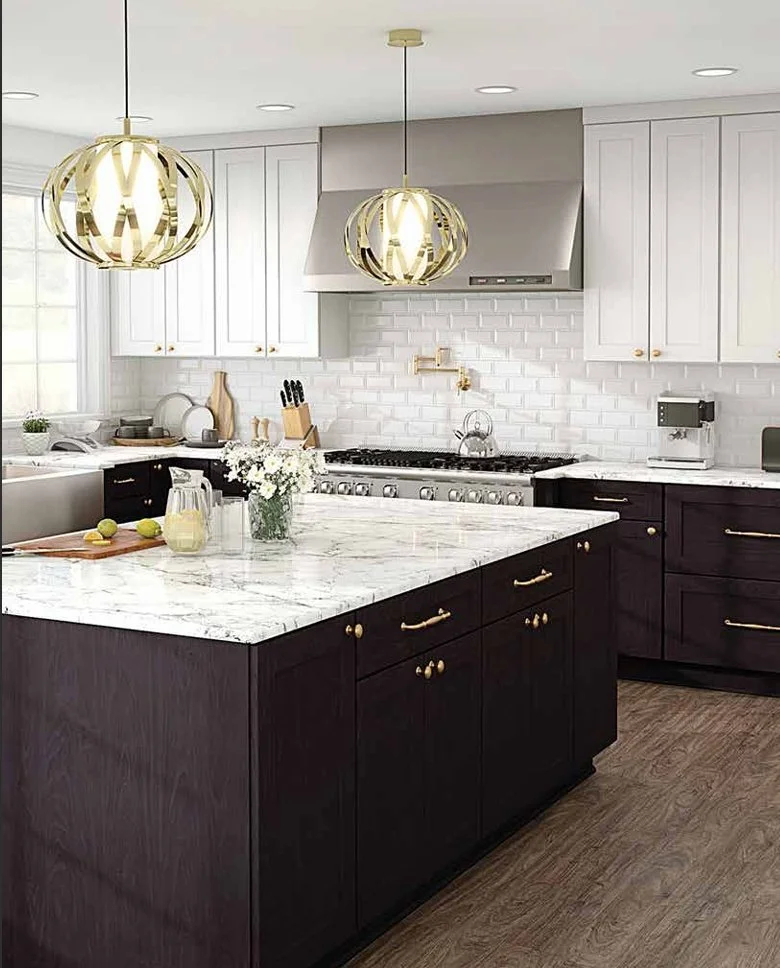 Modern kitchen with white upper cabinets, dark lower cabinets, marbled white countertops, a large kitchen island, two gold pendant lights, white subway tile backsplash, stainless steel appliances, and wooden flooring.