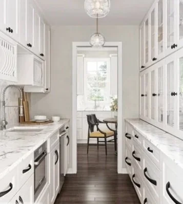 Bright white kitchen with upper and lower cabinets, a window with sunlight, and a small dining area with a table and chairs in the background.