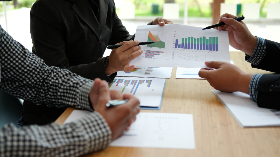A friendly financial advisor explaining simple wealth-building concepts to a couple during a consultation.