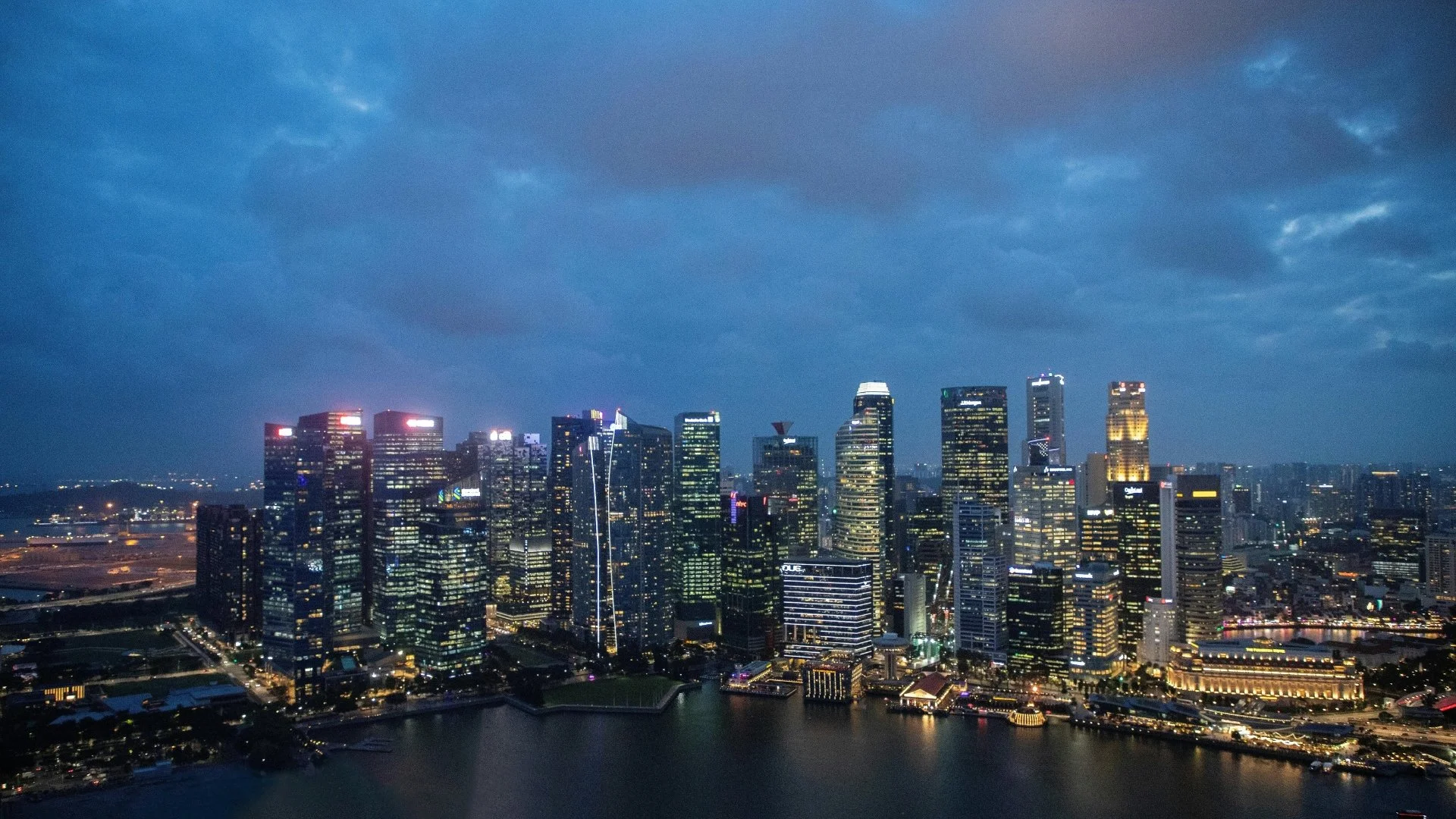 An expansive view of the Singapore financial district at dusk, showing the lights of the CBD