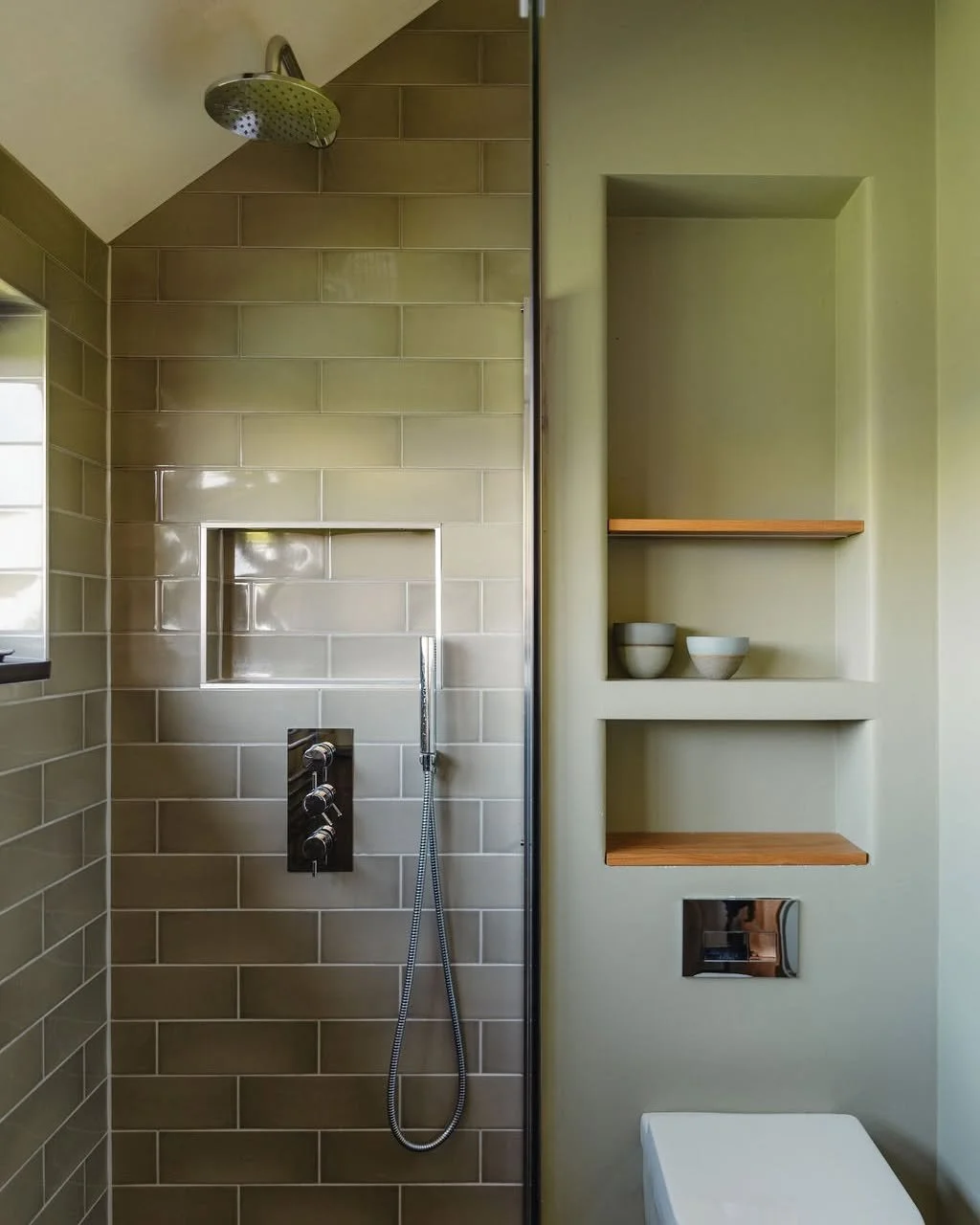Calm, functional, and beautifully considered.

In this downstairs shower room, every detail has a purpose, from the recessed shelving and oak accents to the soft, earthy tones of the tiles. By combining natural textures with clean lines, we created a