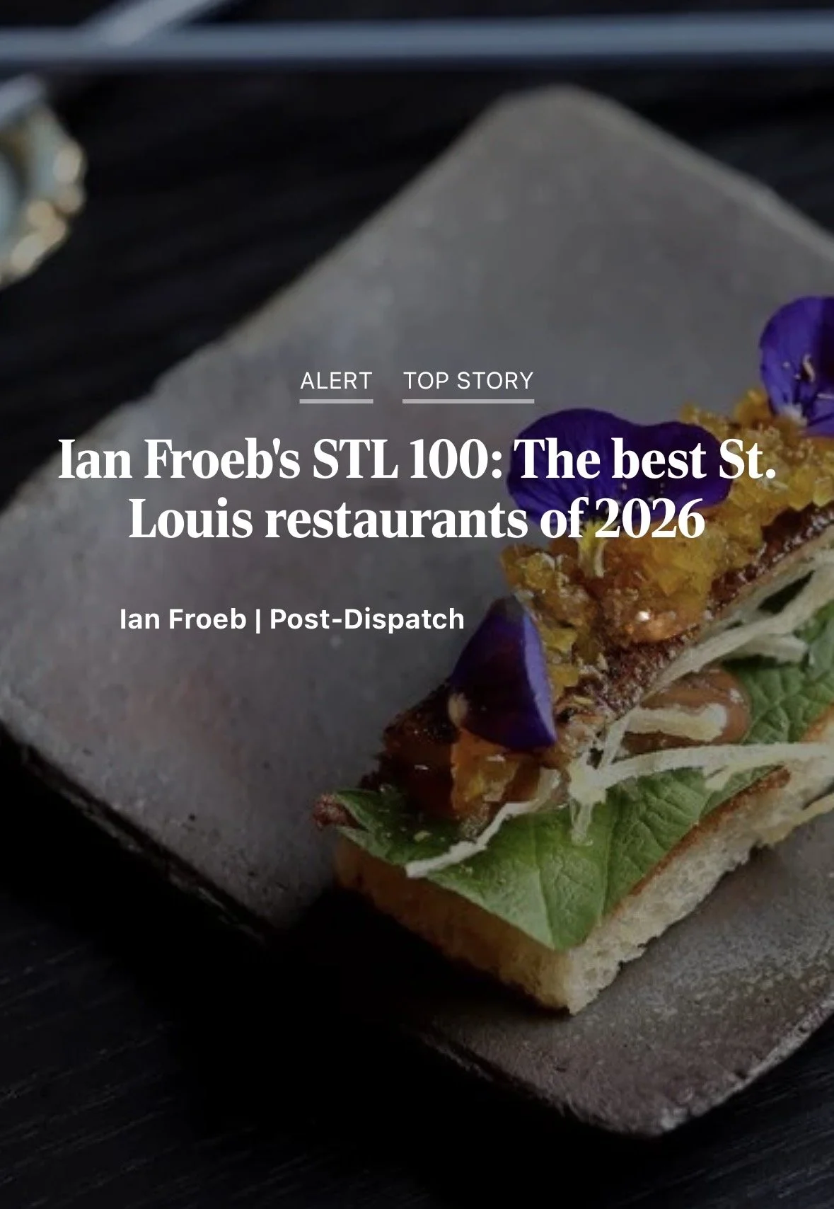 Cover of an article featuring a close-up of a plated French-style dish with edible flowers, herbs, and garnishes for a restaurant review.