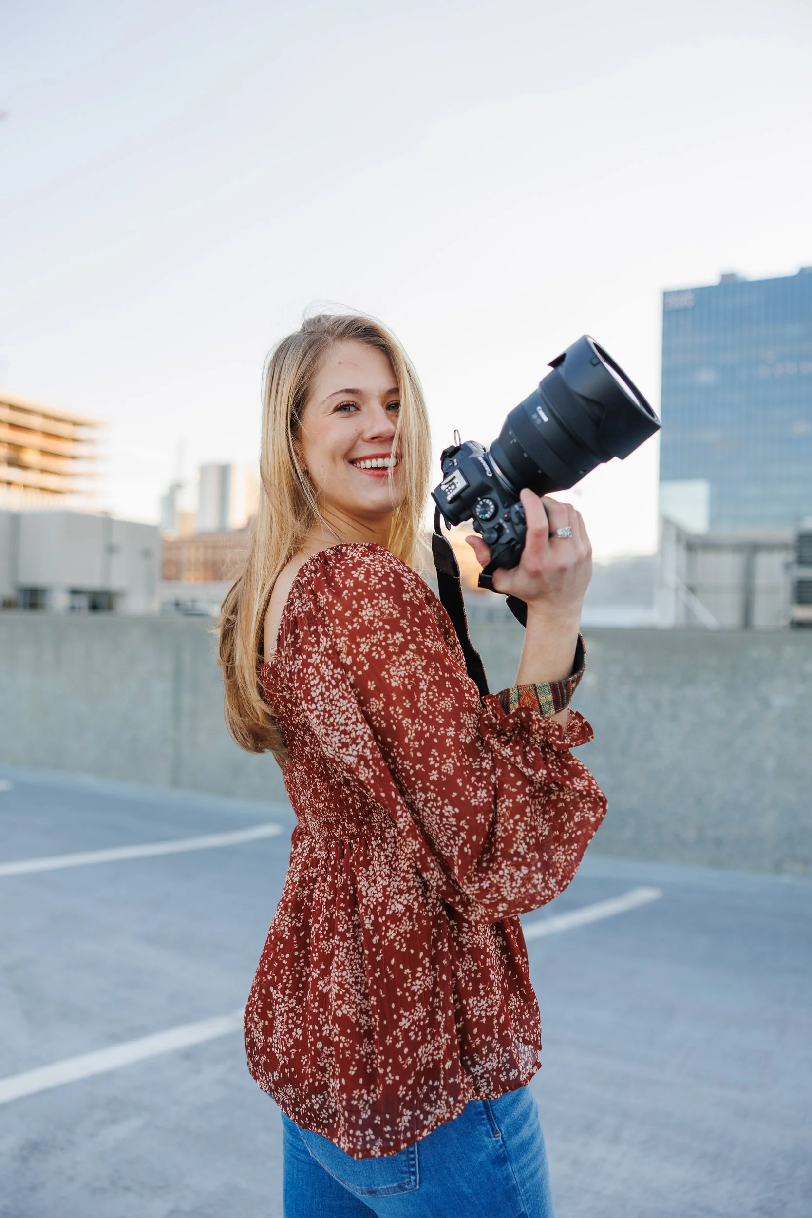 Wedding photographer Daniela Conroy holding camera on rooftop in Atlanta Georgia