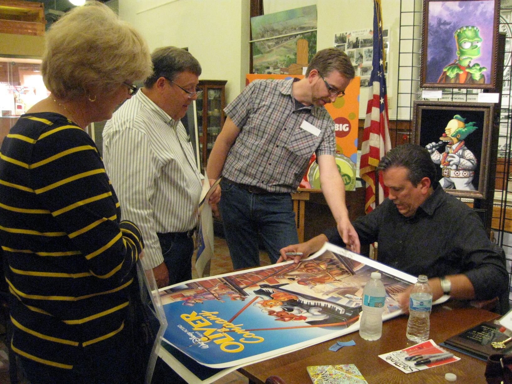 Bill Morrison, seated at right, greets guests and signs posters at the opening night reception