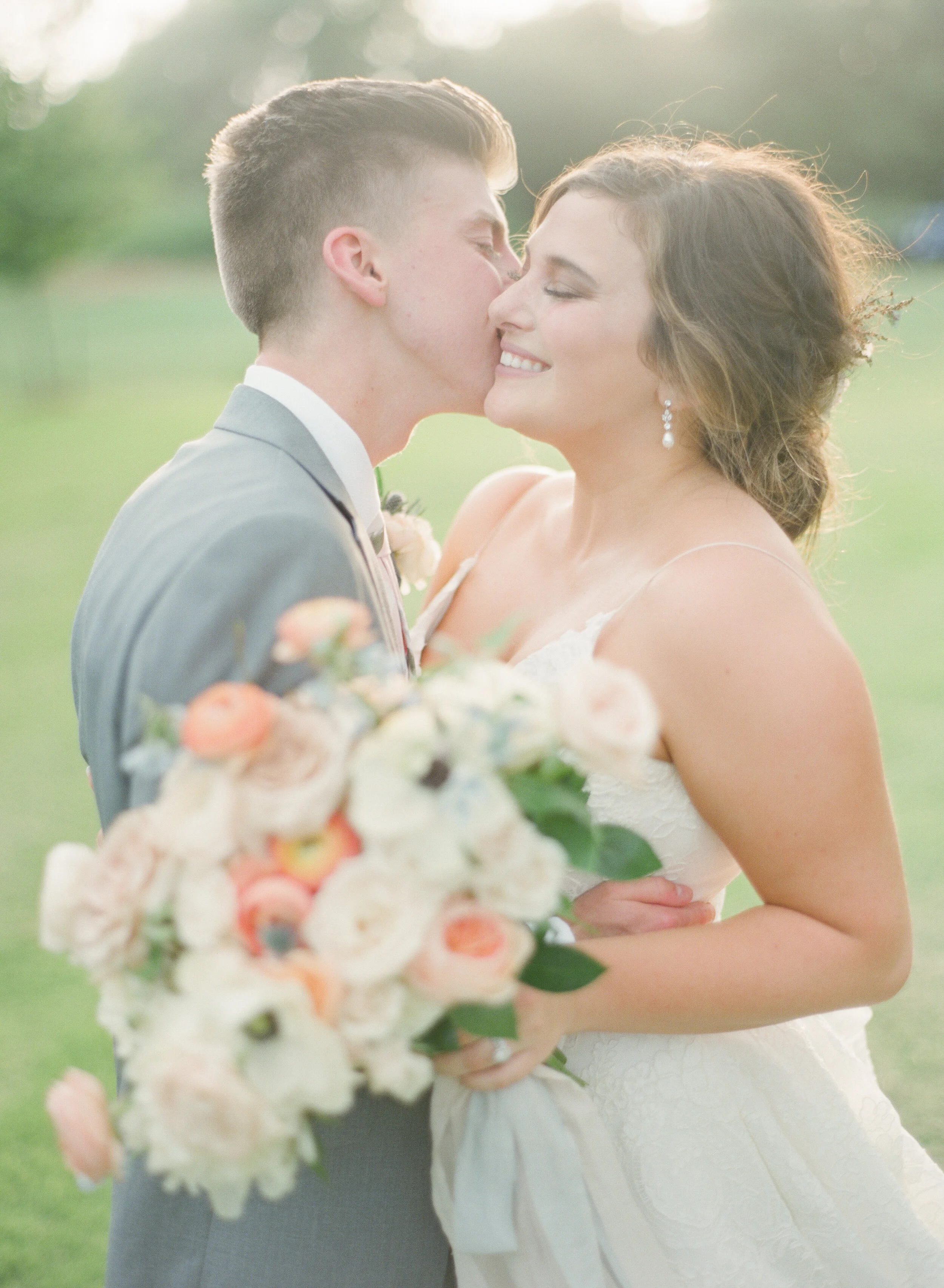 The Baumberhof fine art film wedding photographer couple kissing during golden hour with organic bouquet - Oklahoma City Wedding Photographer