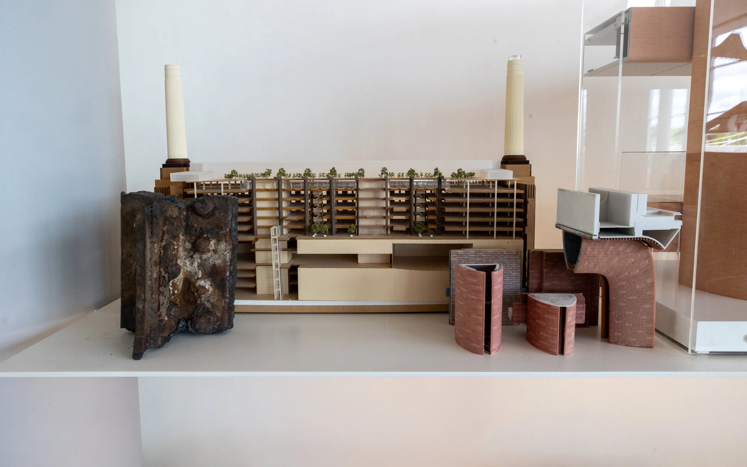 Architectural model of a building with two tall columns, greenery on the roof, and various interior and exterior structures.