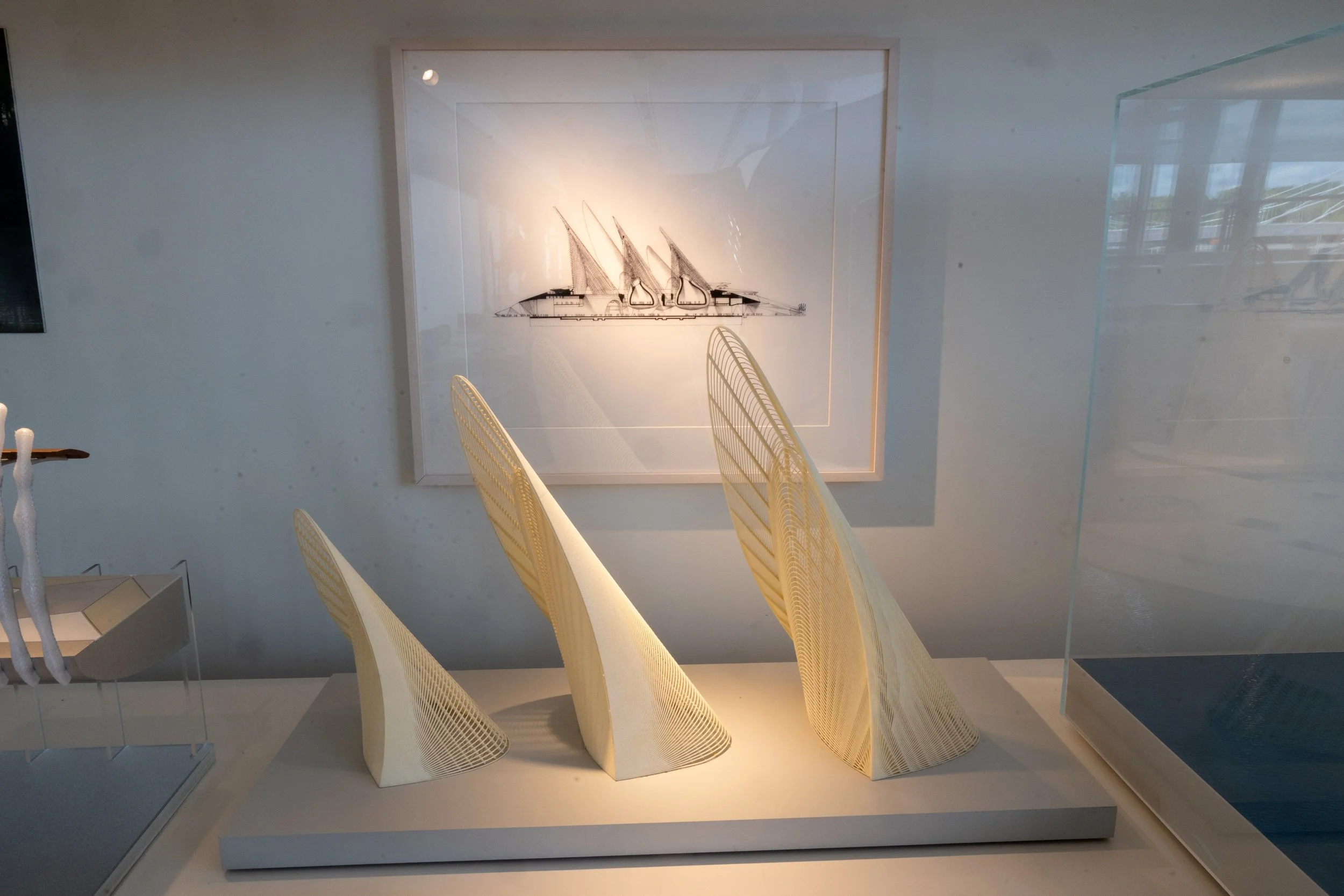 Modern sculptures resembling sails or fins on a white pedestal in an art gallery.