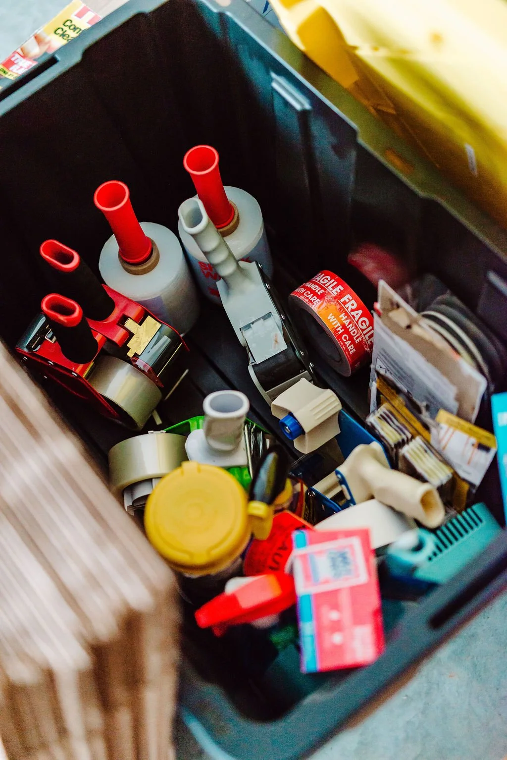 Inside a black toolbox with various repair supplies including red-handled screwdrivers, electrical tape, glue bottles, and small tools.