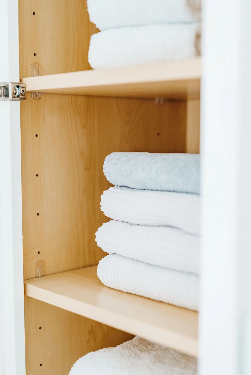 Shelves inside a cabinet with neatly folded white towels.