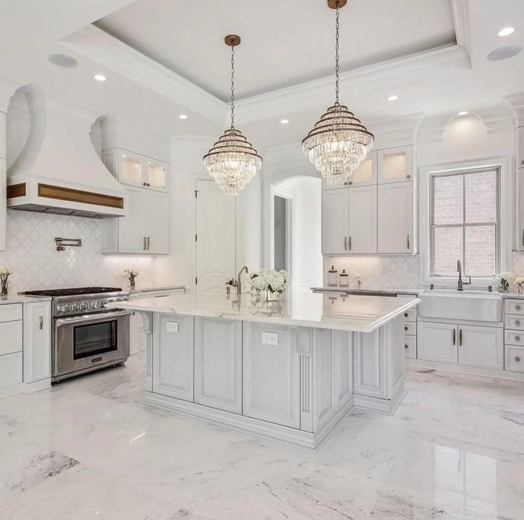 A beautifully styled kitchen with a dramatic natural stone island — warm, layered, editorial lighting