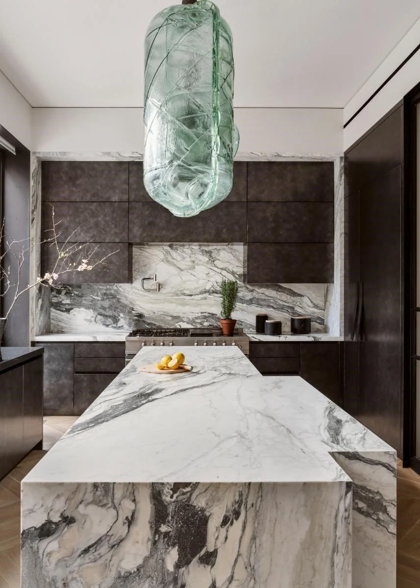 A stunning marble kitchen — white or cream with dramatic veining — beautifully styled with European elegance