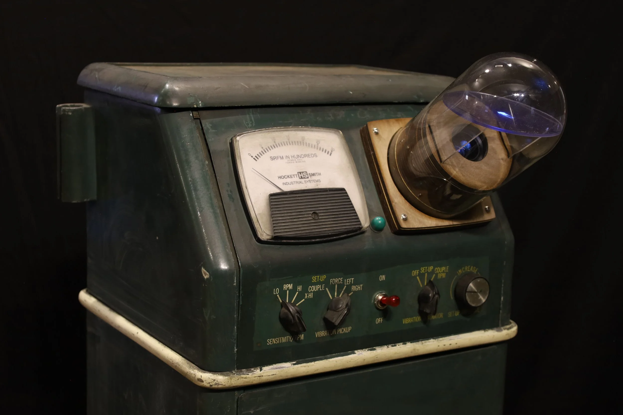  Mr. Hockett's Lawnmower Shop , 2024, surplus tire balancing machine, glass dome, digital projector, media player, audio player, acrylic sheet, wood, digital print

