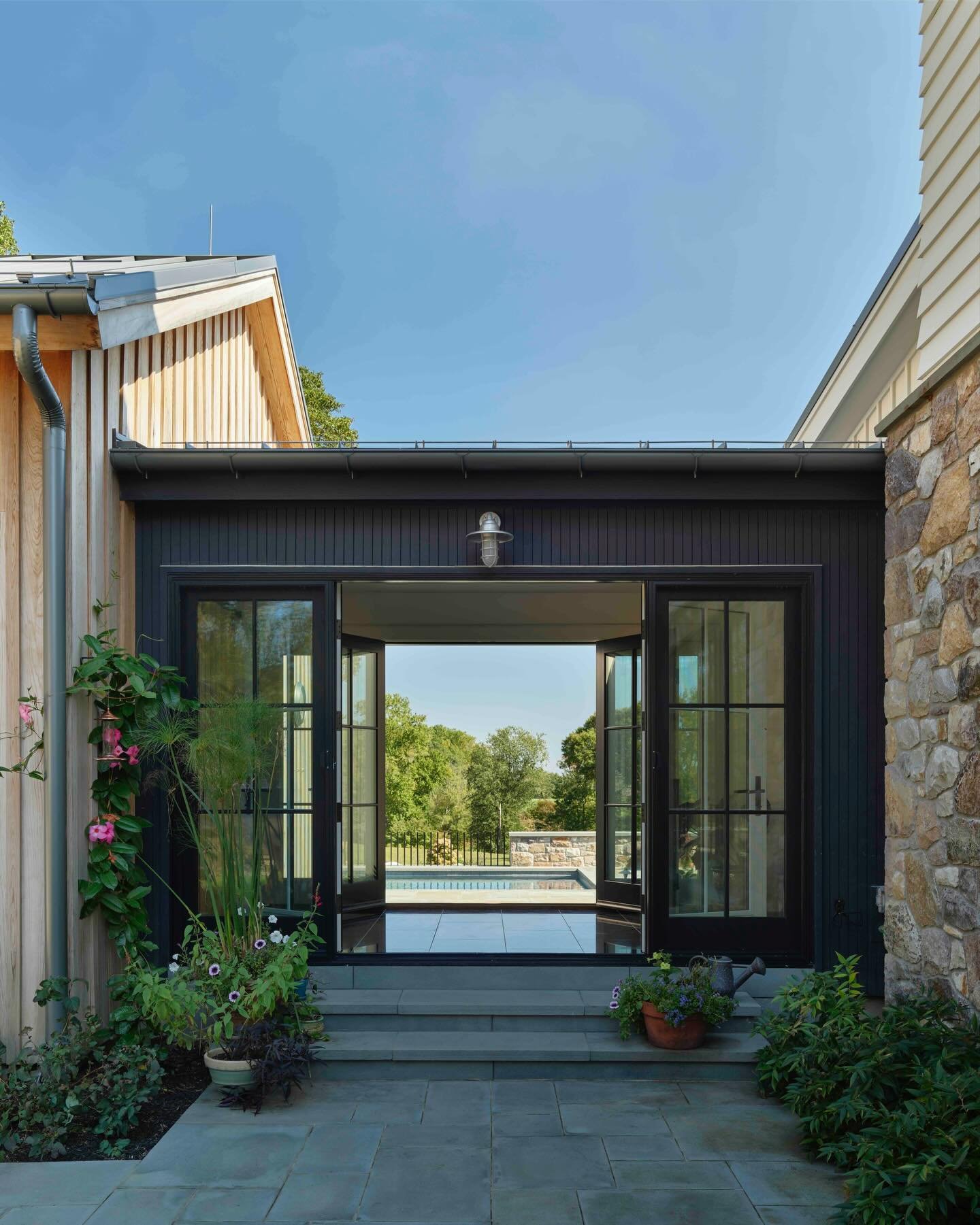 As the cold settles in, I&rsquo;m revisiting summer: wide-open views framed by buildings and hardscape  #pool #farmhouse #stonewall