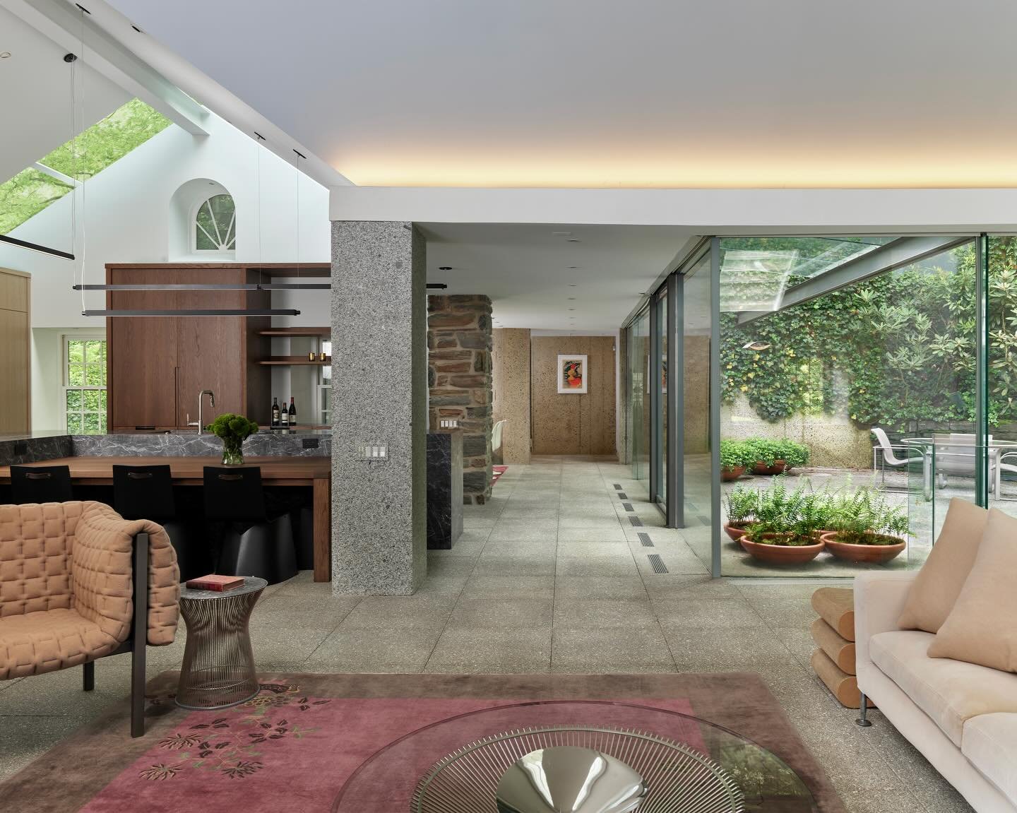 STONE behind glass is a stone house nestled along a wooded creek in Gladwyne, Pennsylvania. We reimagined the home embracing an open plan, expansive glazing, and a series of bold sectional gestures&mdash;visually connecting living spaces across level