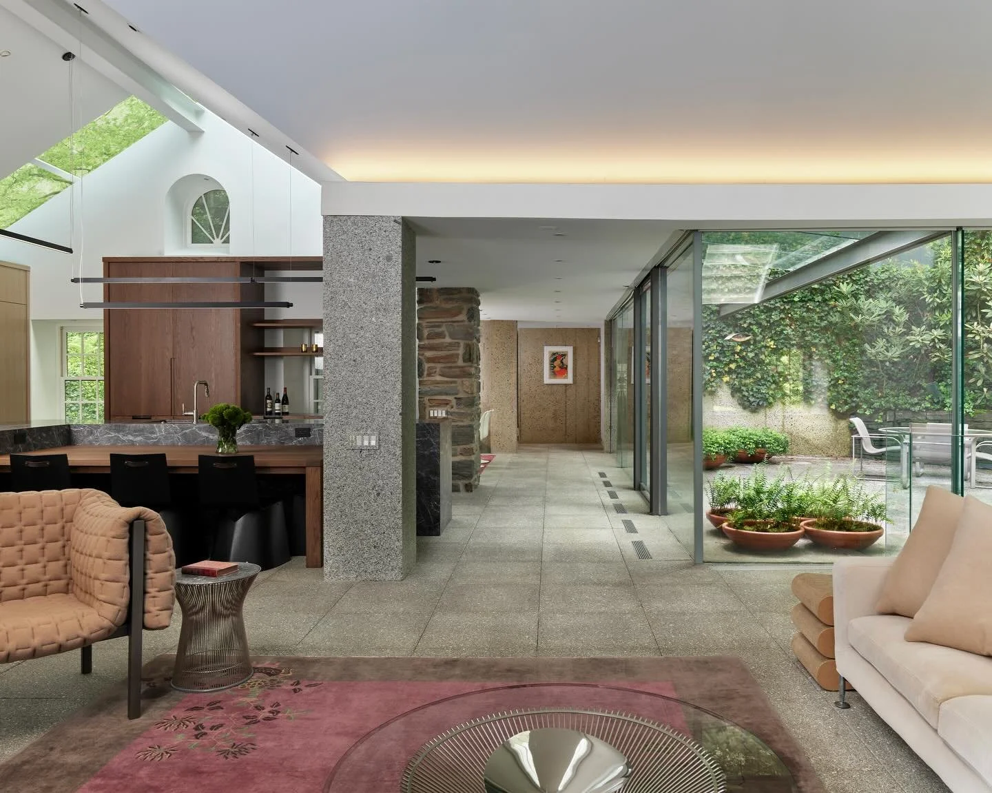 STONE behind glass is a stone house nestled along a wooded creek in Gladwyne, Pennsylvania. We reimagined the home embracing an open plan, expansive glazing, and a series of bold sectional gestures&mdash;visually connecting living spaces across level