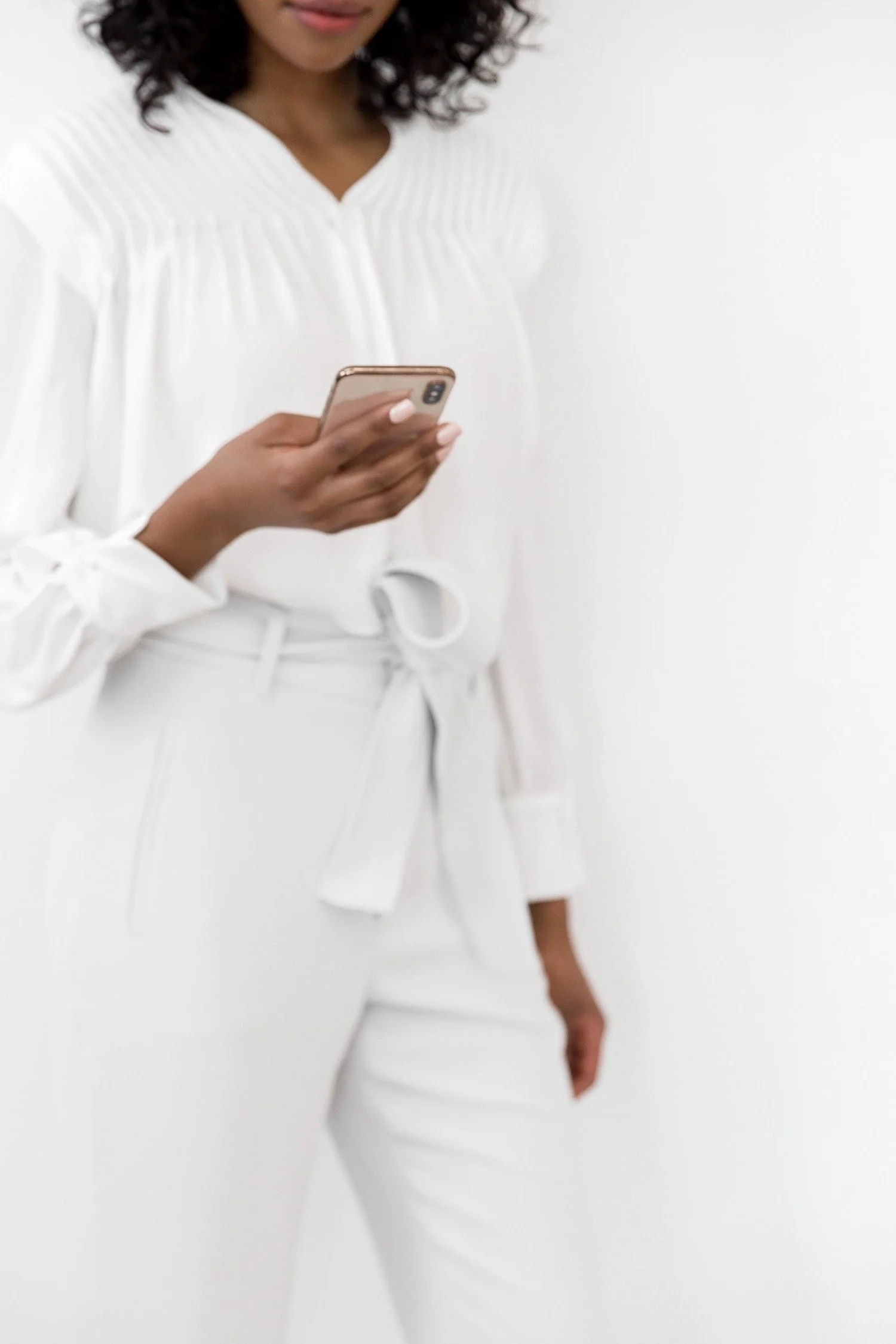 Black woman holding and looking down at an iPhone in her hand