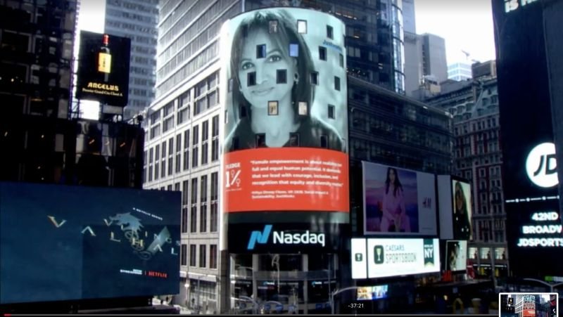 Billboards in Times Square, New York City, including a large Nasdaq ad and a billboard with a woman's face.
