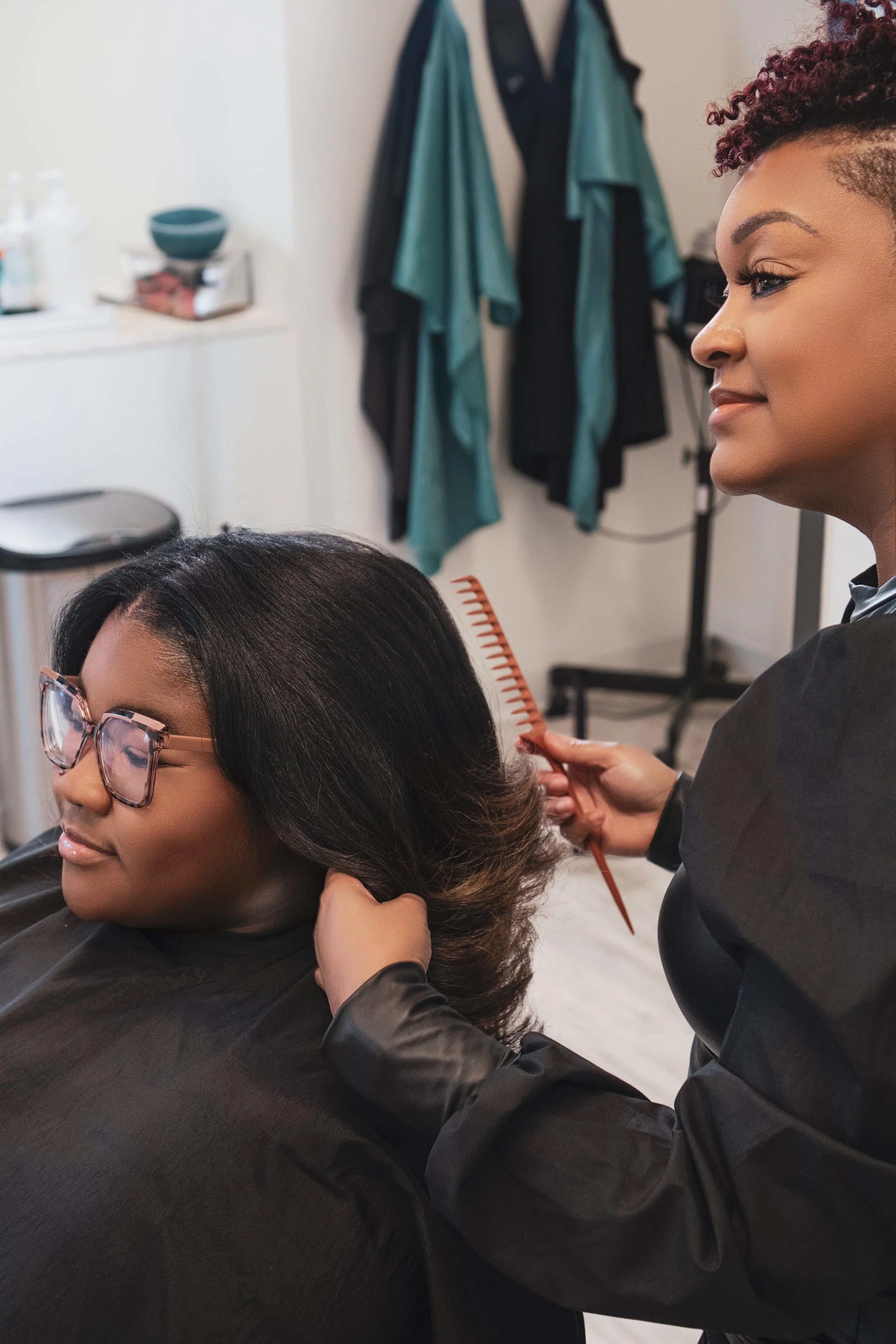 hairstylist combing clients hair while they both look in the mirror and smile