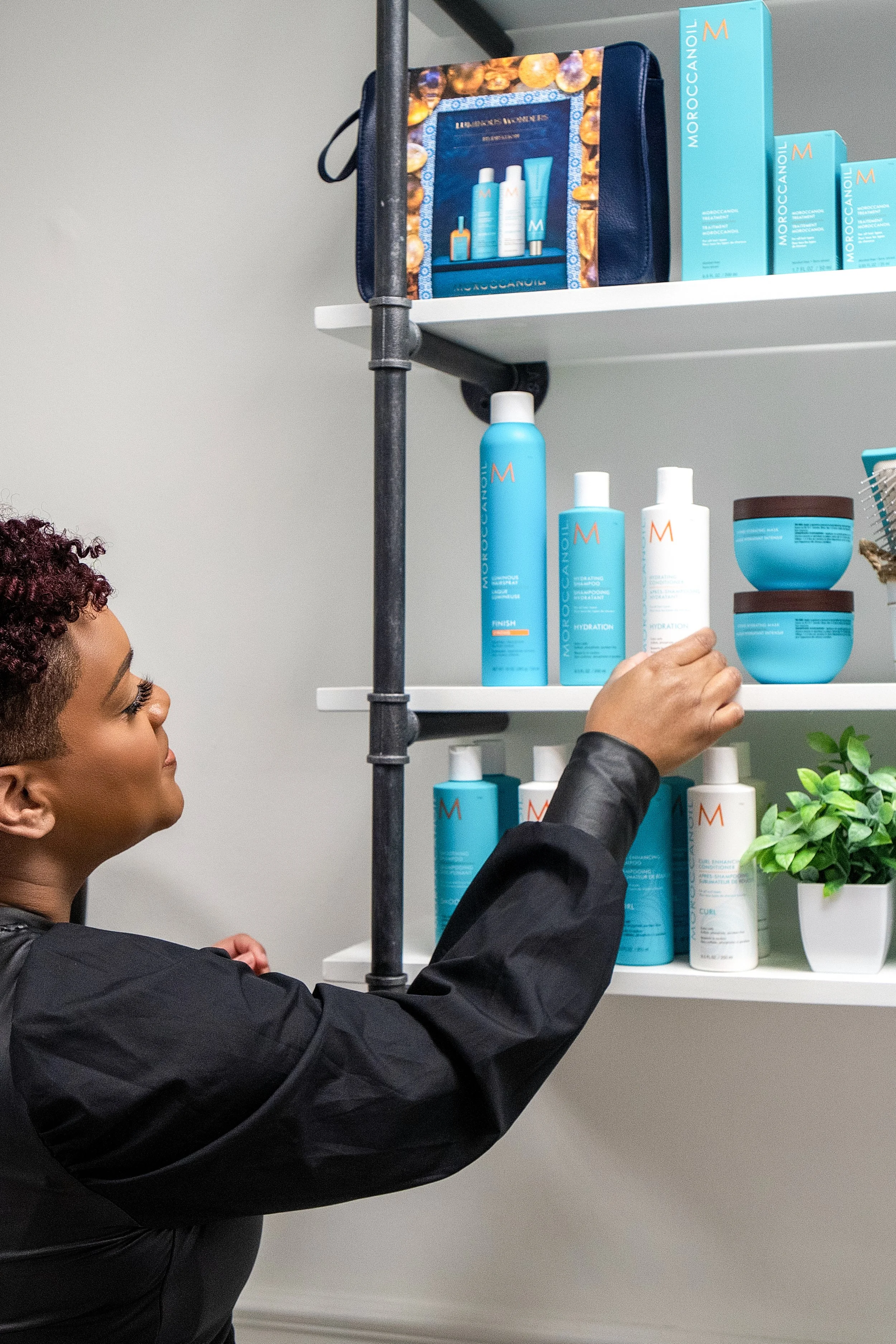 hairstylist putting moroccanoil retail products on the shelf in her salon
