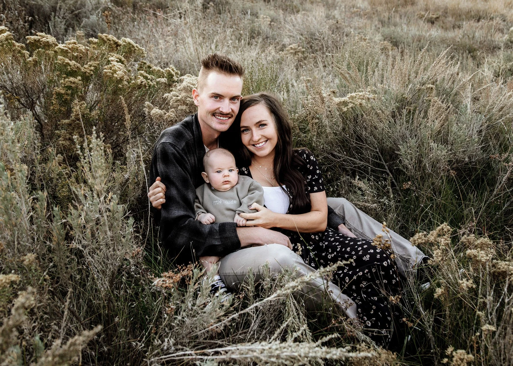 Family posing with mountains, rocks, and river in the background