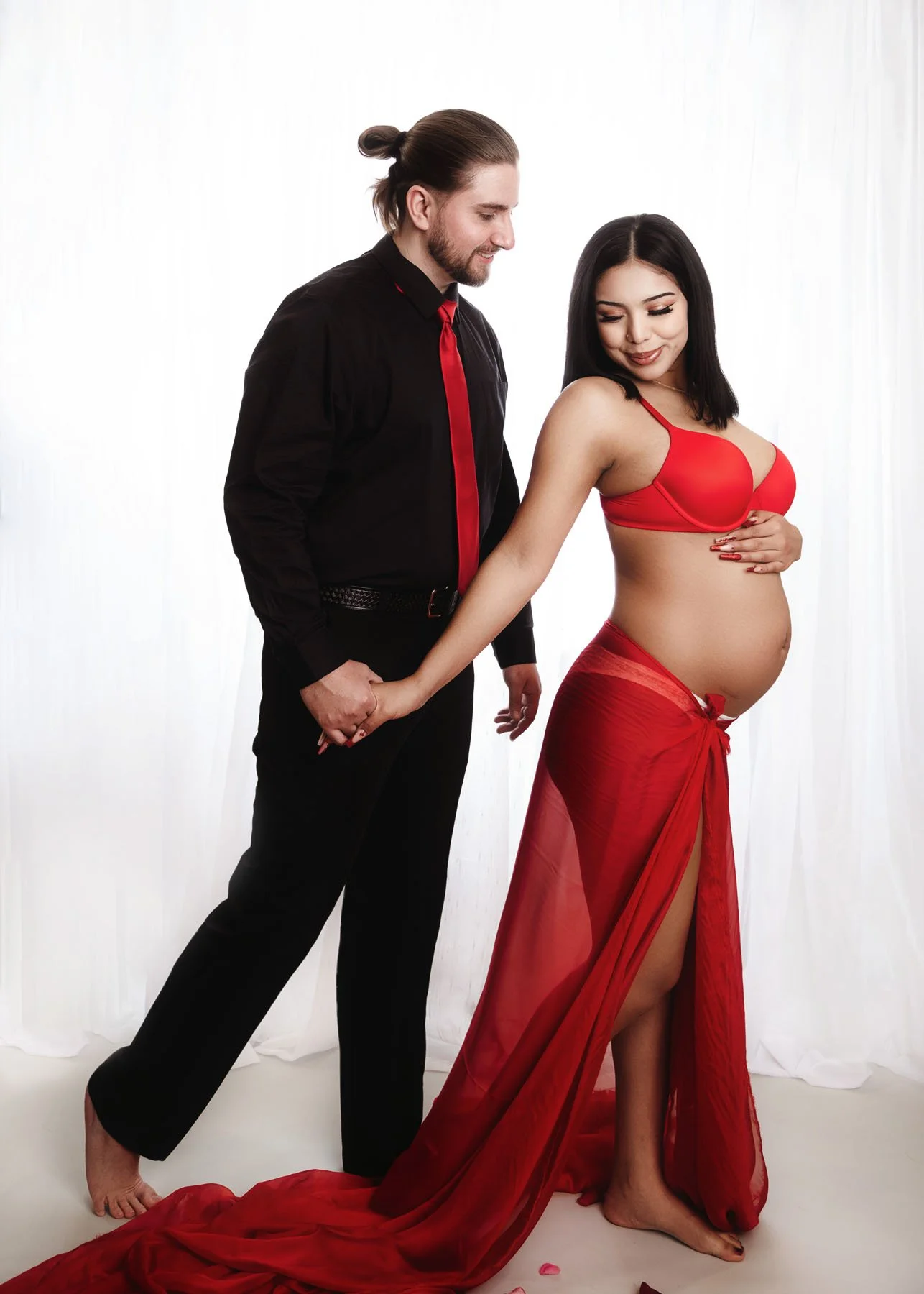 Mama walking away from camera holding daddy's hand, hands on baby bump