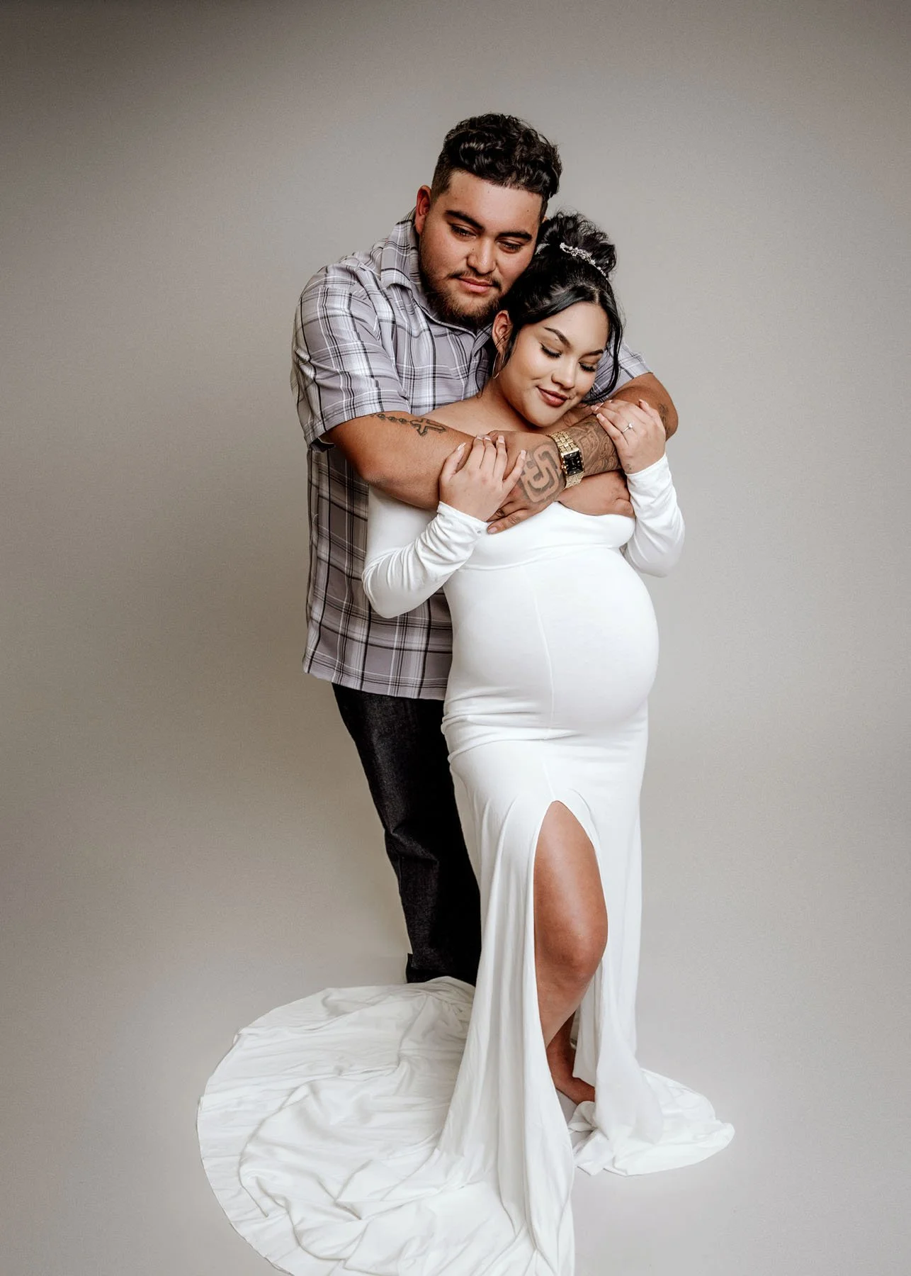 Daddy standing behind mama holding her shoulders, baby bump visible